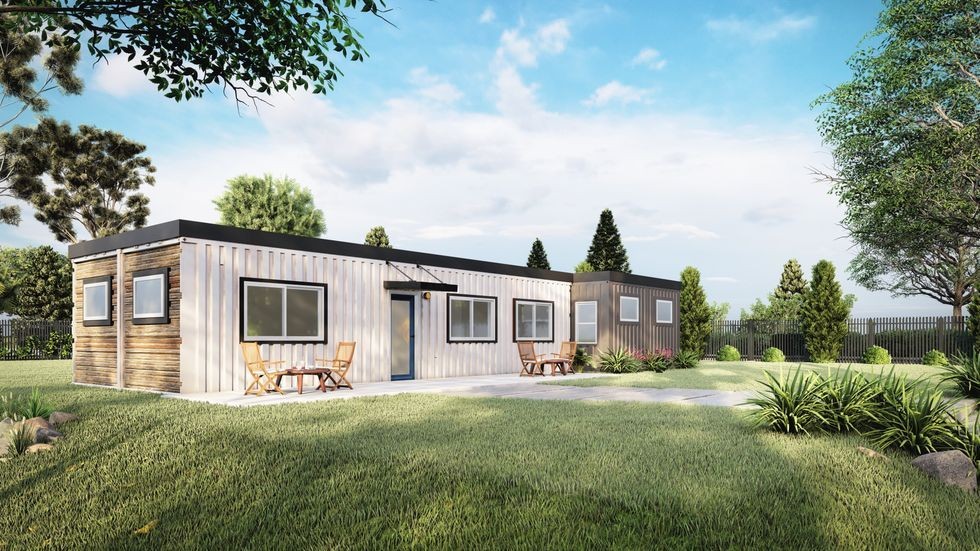 Modern modular home made from shipping containers in a grassy yard with trees and outdoor seating.